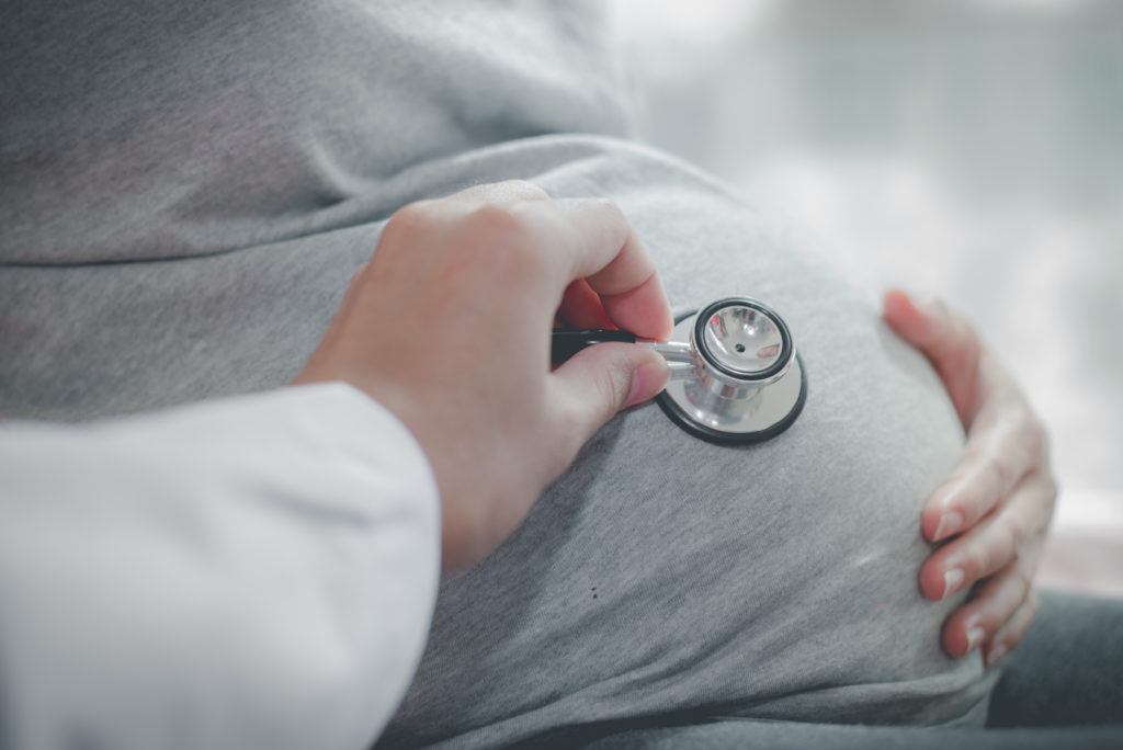Doctor checking pregnant woman with stethoscope