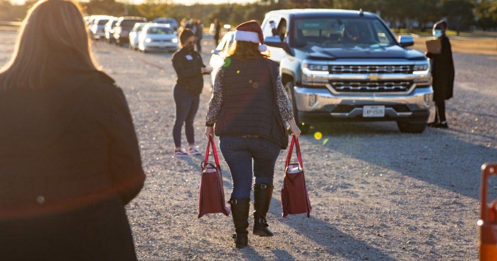 a photo of volunteers handing out care packages at a drive thru distribution event