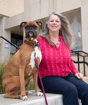 a boxer dog seated next to his female owner