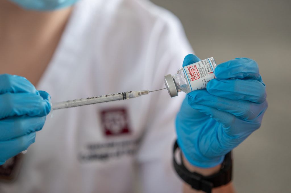 close up of a student holding a syringe preparing a dose of the vaccine