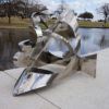 a steel sculpture displayed in front of a pond