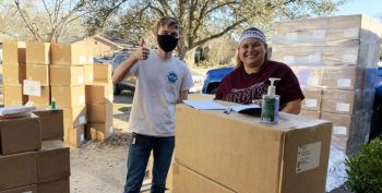 Two students standing with stacks of boxes