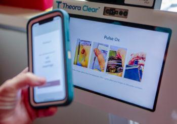close up image of a person holding their cell phone up to the screen of a kiosk