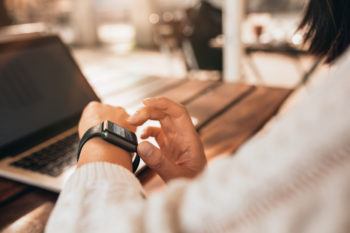 close up of a woman looking at a smartwatch at a cafe