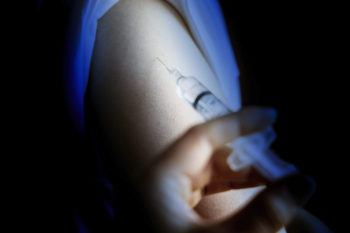 close up image in shadow of a person receiving a vaccine