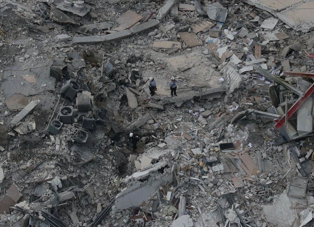 aerial view of two rescue workers standing in the rubble pile
