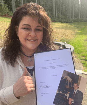 portrait of joni lara giving a gig 'em holding a copy of the final paper and a photo of her father