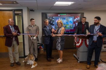 ellie and don knauss cut a ribbon as reveille and handler, others look on