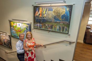 Don and Ellie Knauss standing on staircase posing next to framed artwork