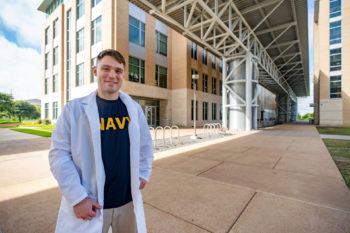 portrait of andrew chapman in medical coat standing outside agrilife building