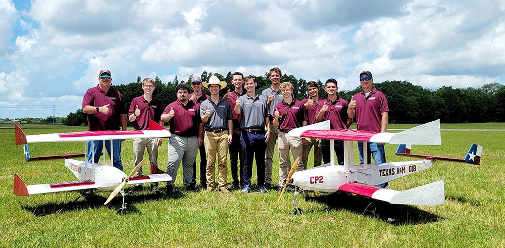 group photo of the team next to their aircraft