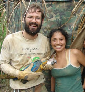 a man and a woman holding a macaw