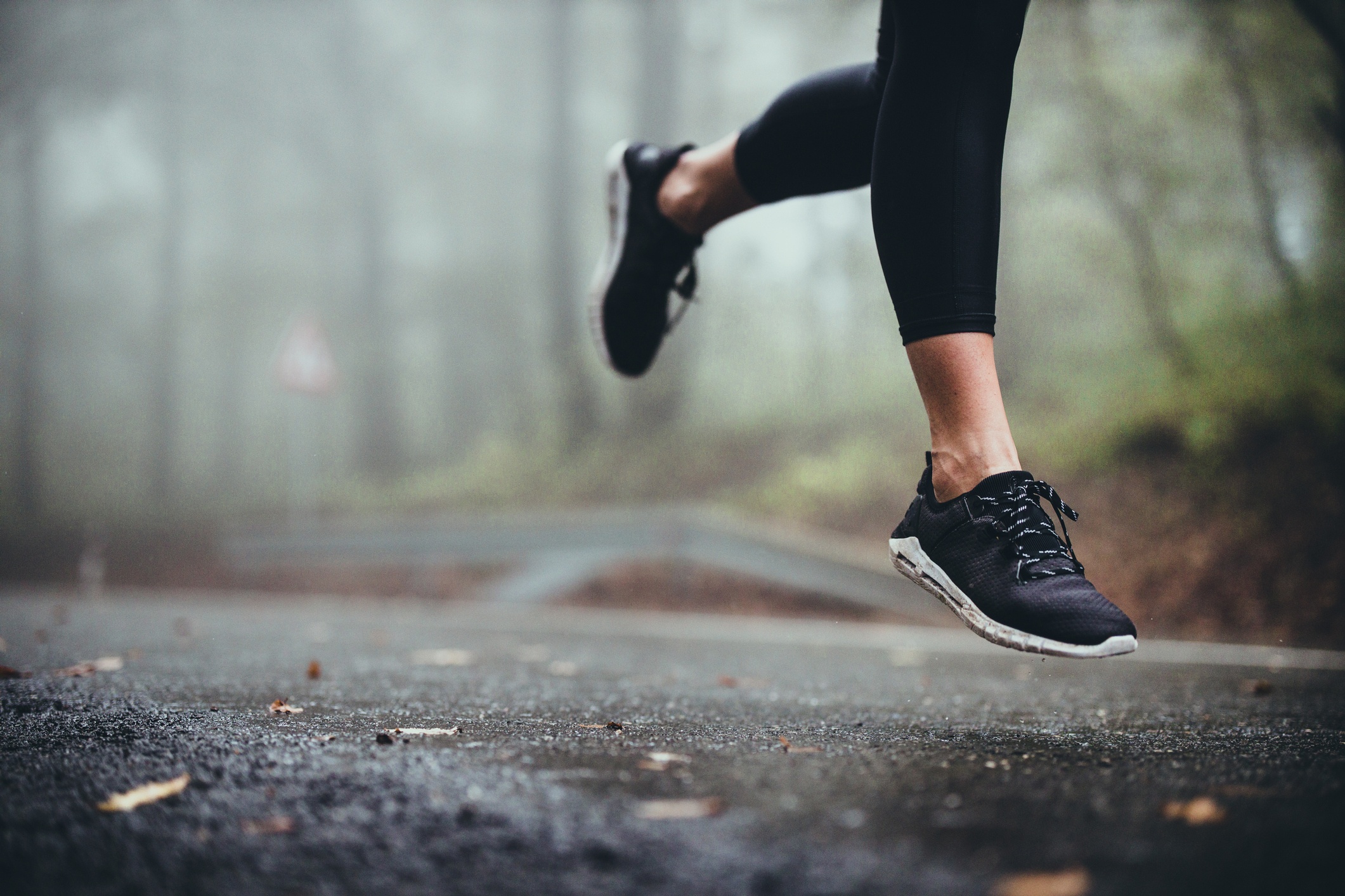 view of a woman's legs running on a road on a foggy day
