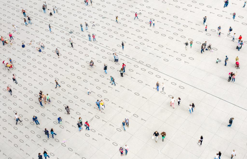 overhead artist's rendering of a crowd of people walking over binary code
