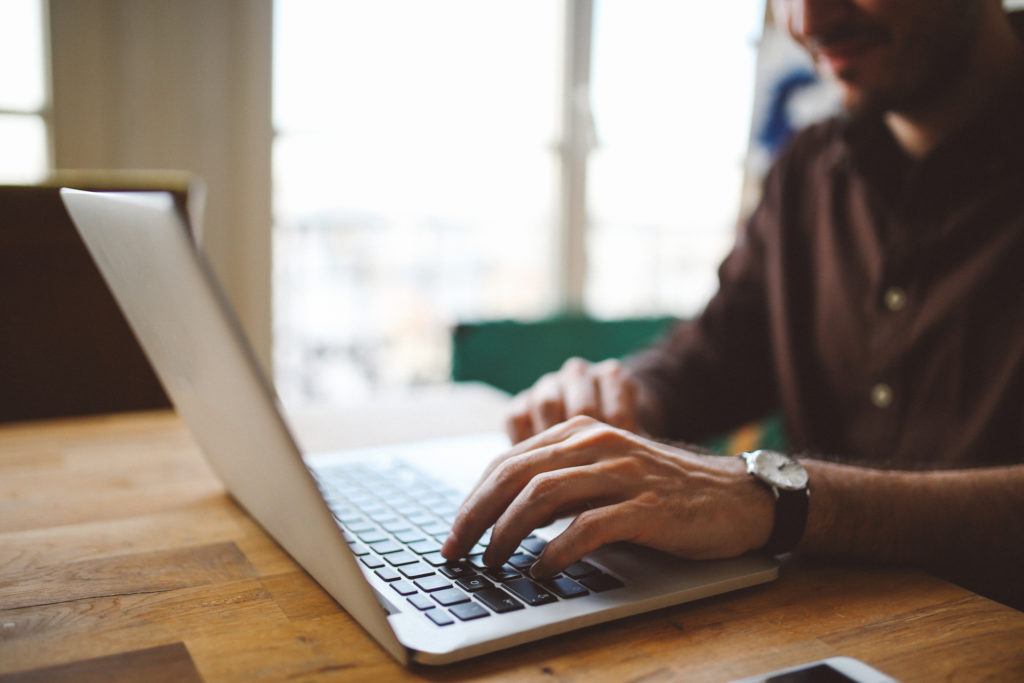 hands of a man working at a laptop on a table