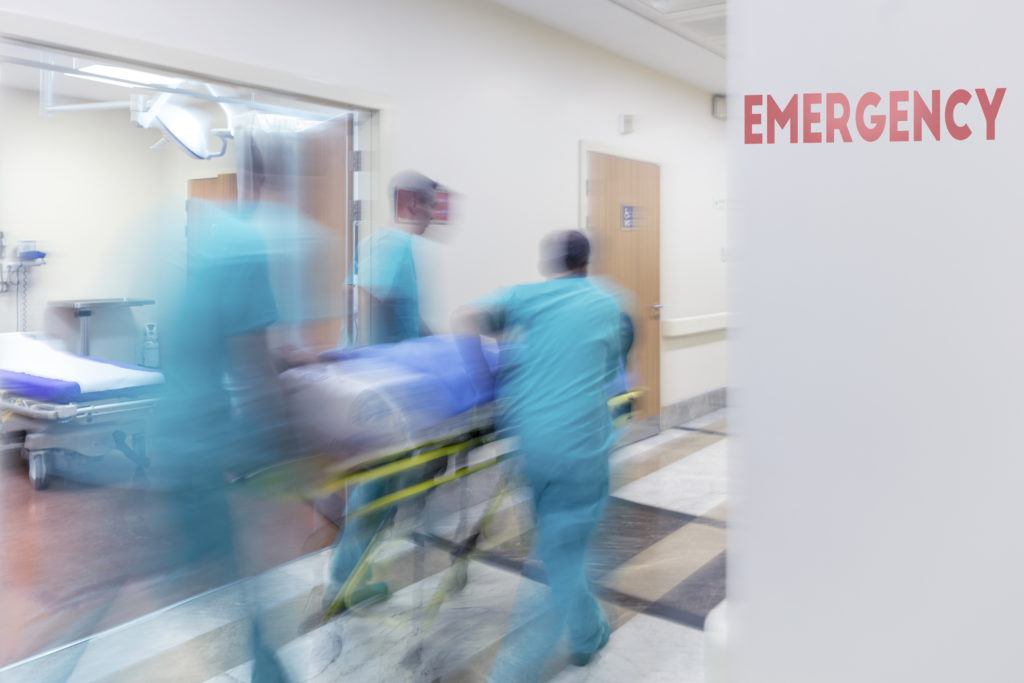 blurred image of doctors wheeling patient through hospital emergency room
