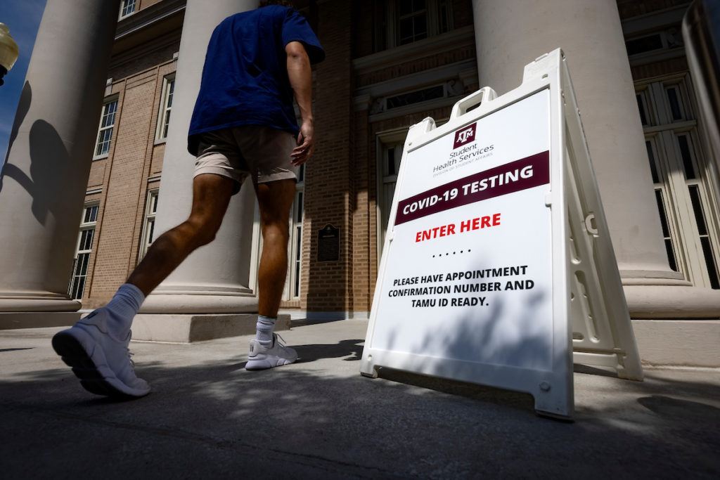 student walking into a building past a sign that says covid-19 testing enter here