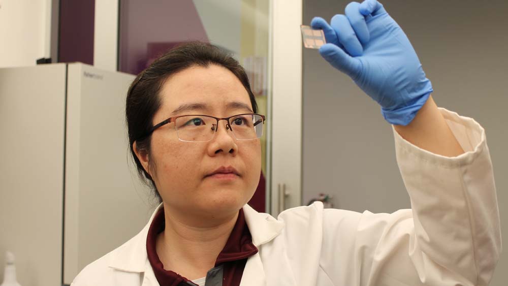 researcher holding a biosensor device up in a lab