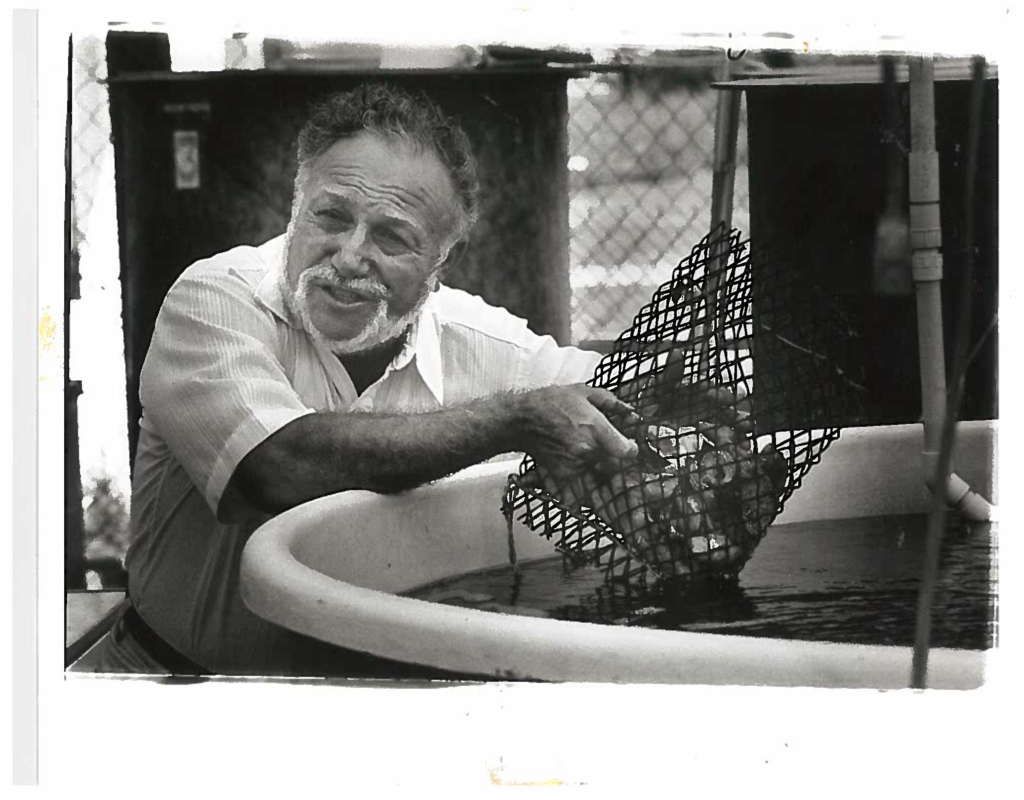 black and white photo of a man next to a tank of oysters
