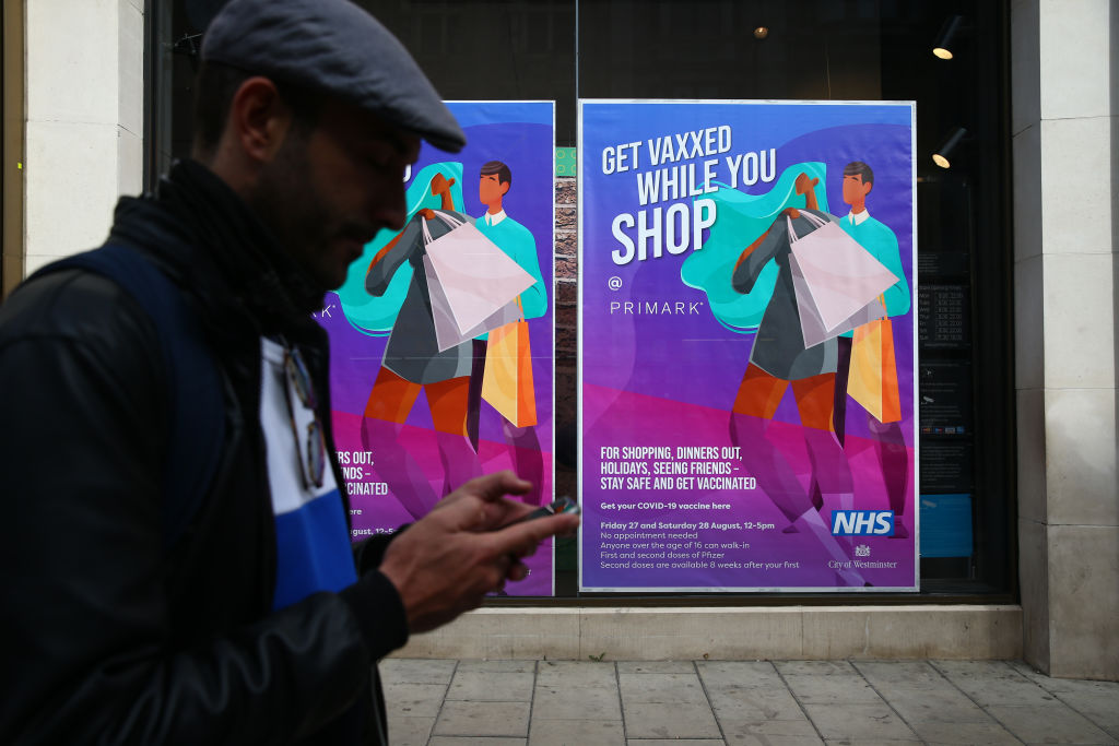 a man walks past a sign advertising in-store vaccinations at a store in london