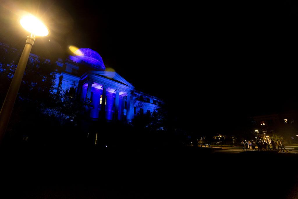 academic building in blue light with a group of students walking in the foreground