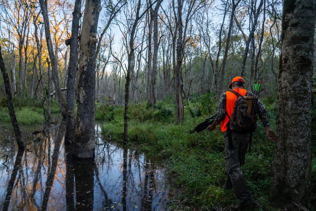 a man wearing orange safety vest walks through a