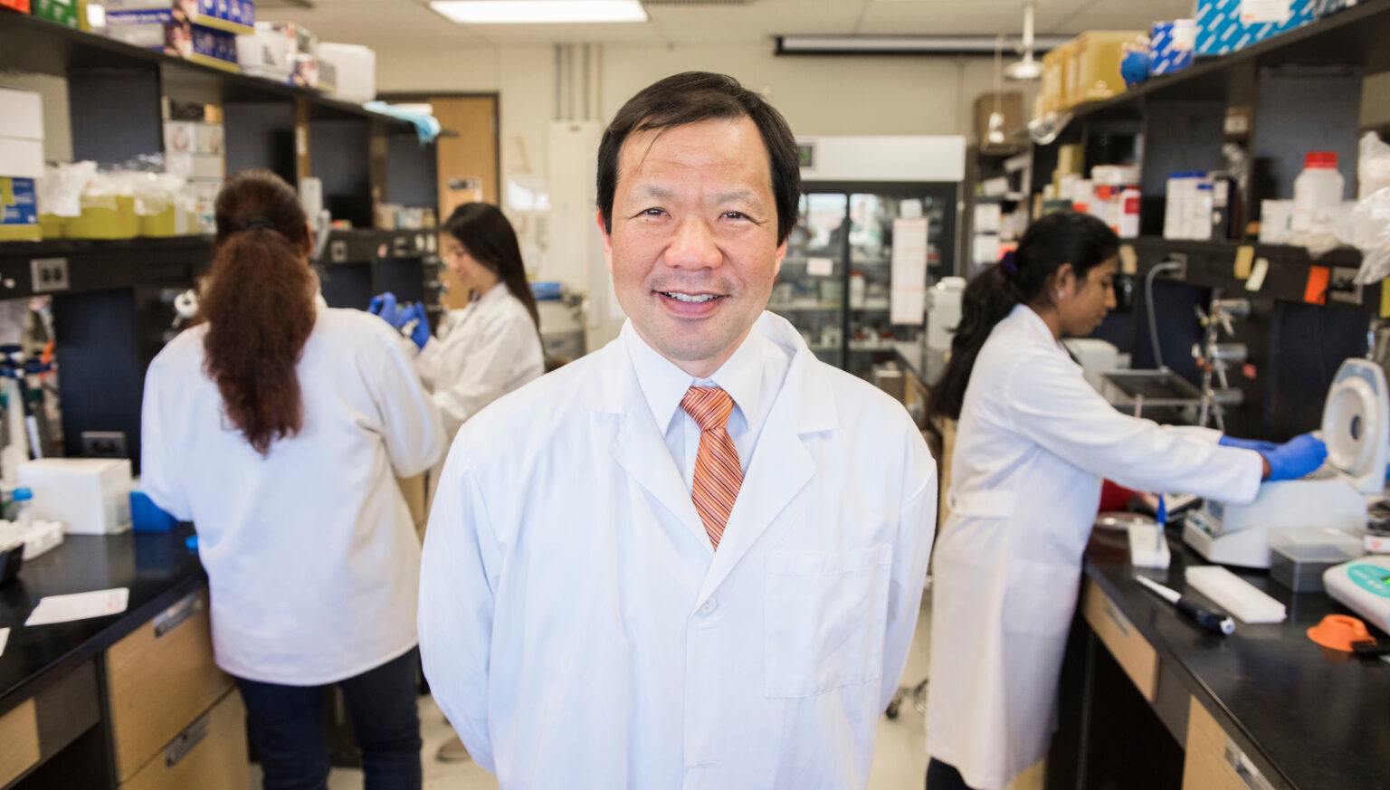 portrait of researcher standing in a lab wearing a white coat