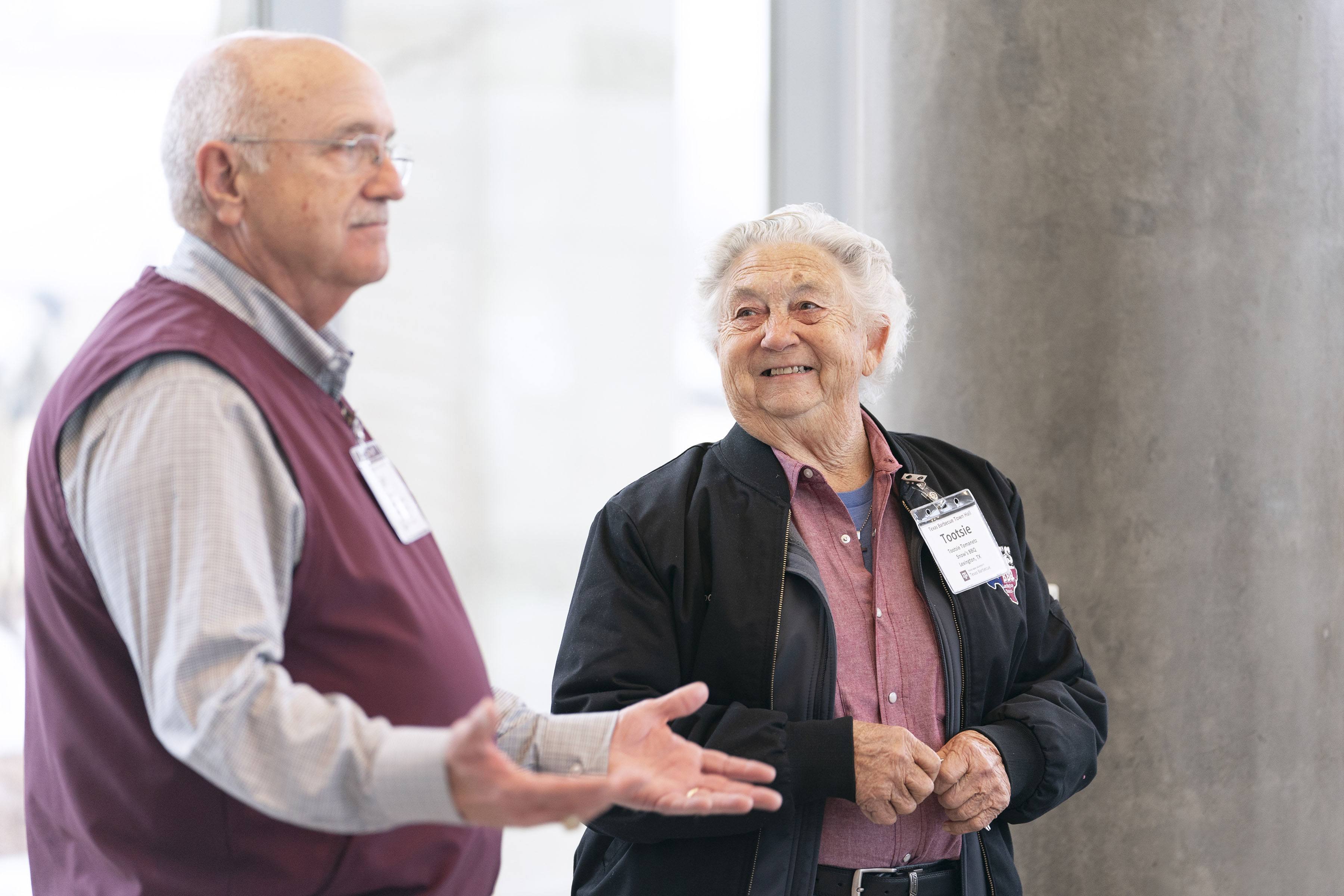 a man and a woman wearing a nametag that says "tootsie" speak at a town hall meeting