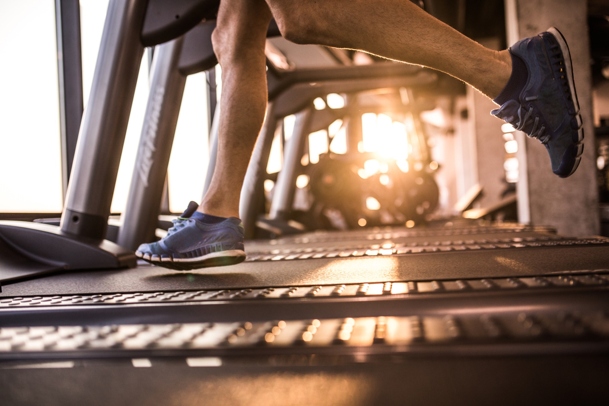 legs of man jogging on a treadmill in a gym