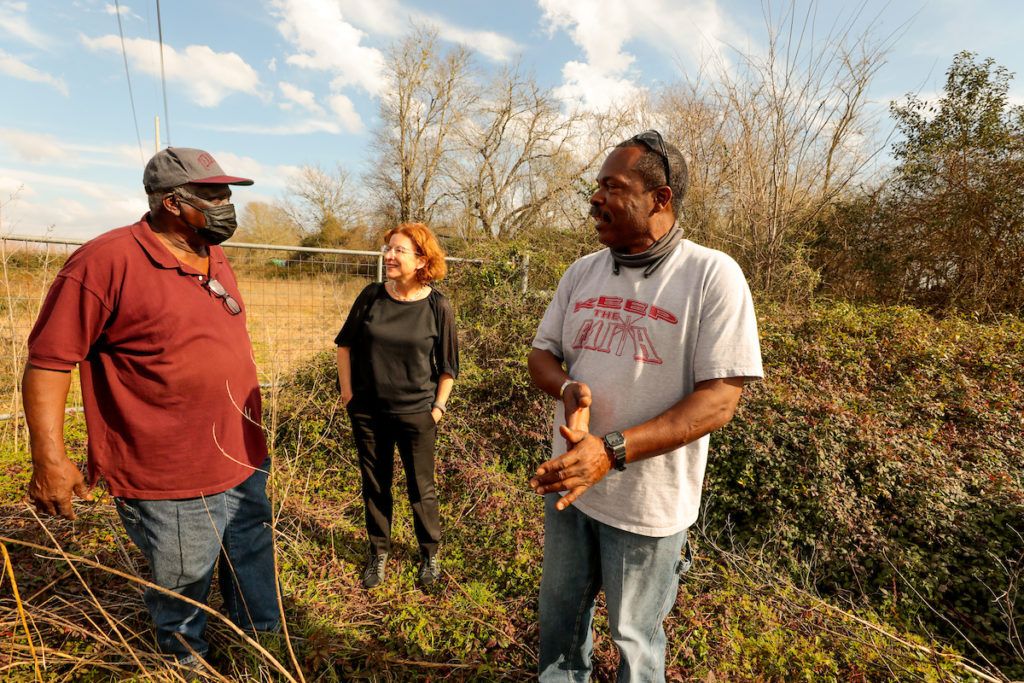 three people stand in a rural property