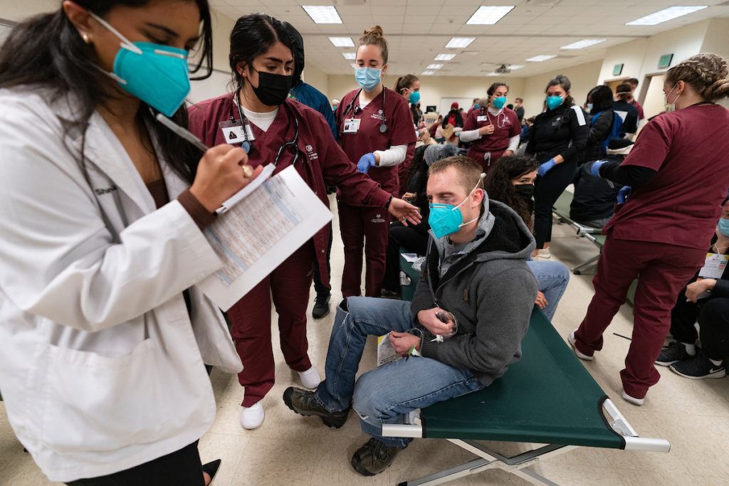 students in a simulated triage area tend to a student acting as a wounded person