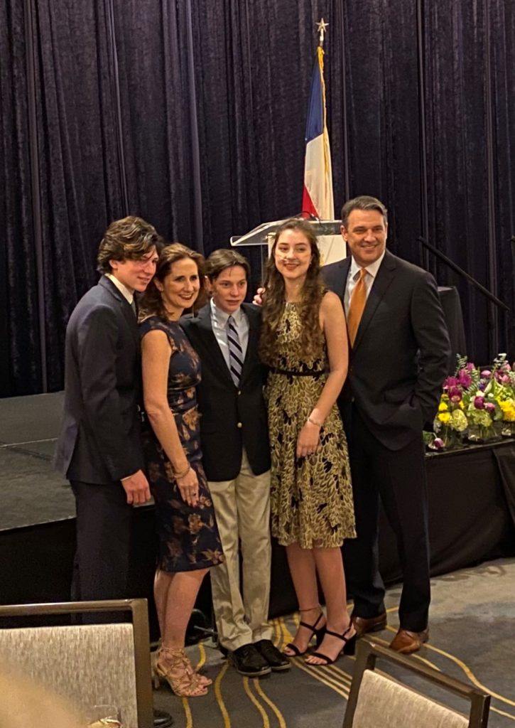 group shot of student and her family in front of a stage
