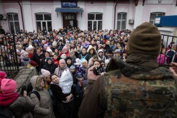 crowd of women and children standing in front of a soldier