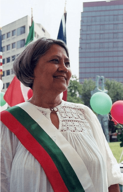 A photo of a woman wearing a red, green and white sash and smiling
