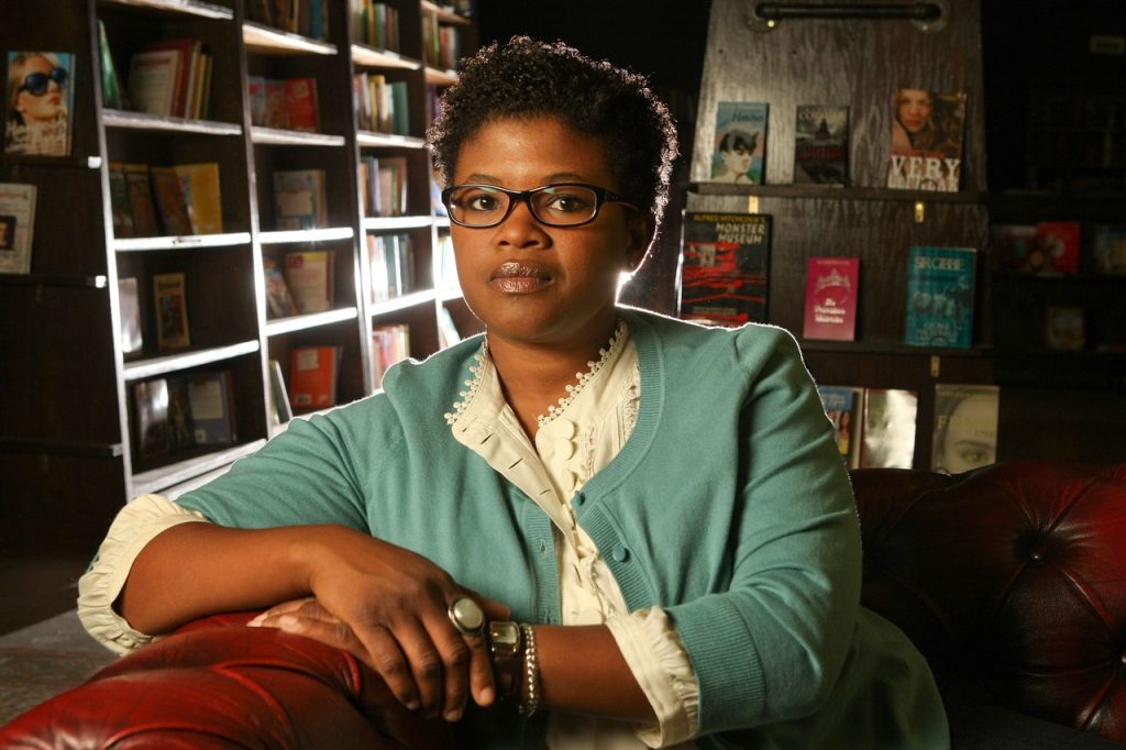 author portrait in a room filled iwth bookcases