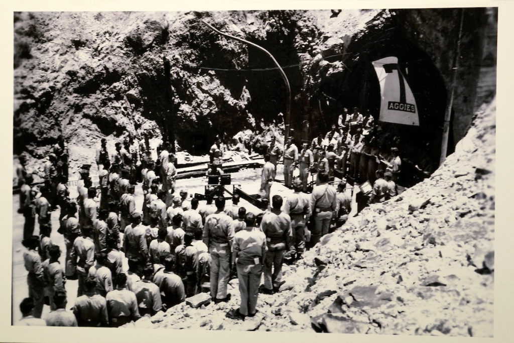 a black and white photo of a group of men standing in front of a tunnel
