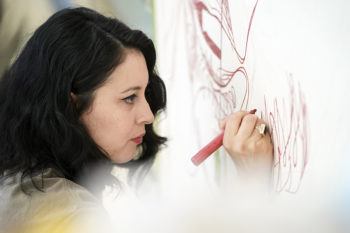 Atlanta-based artist Yehimi Cambrón works on a mural inside the Memorial Student Center at Texas A&M