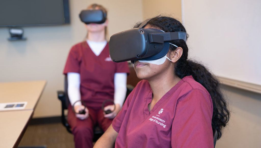 two students sitting at a table wearing VR headsets