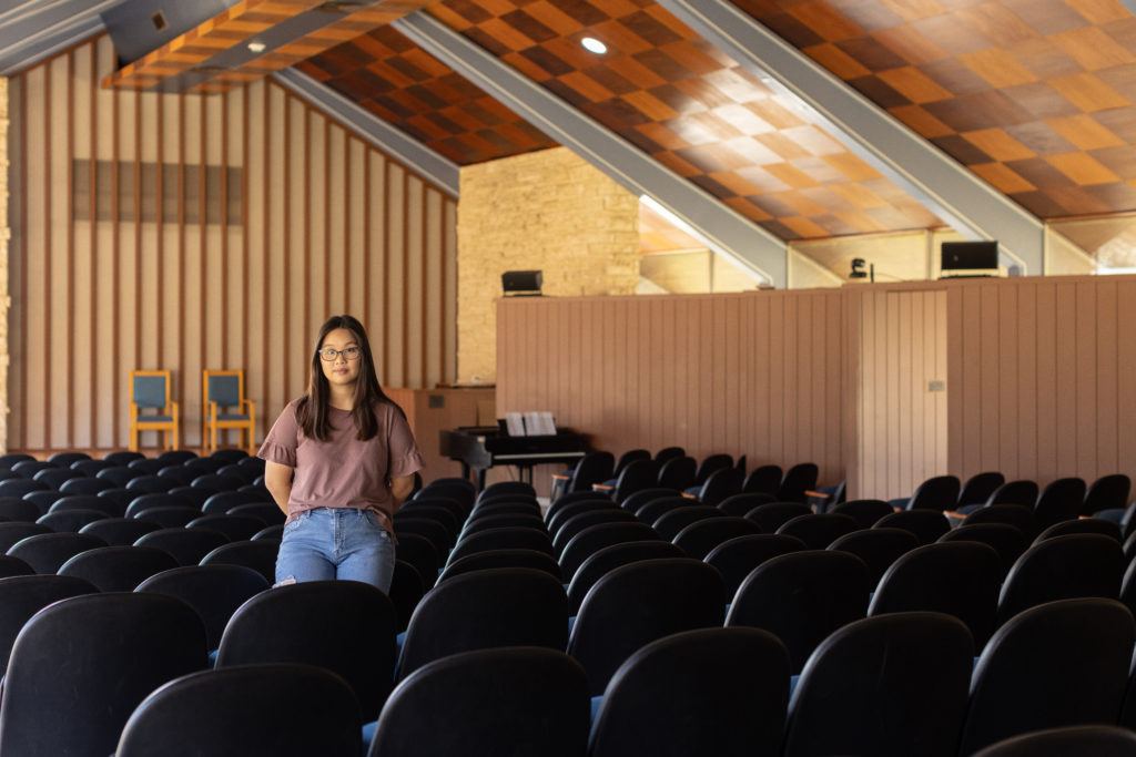 a photo of a woman leaning against a bunch of seats inside a chapel