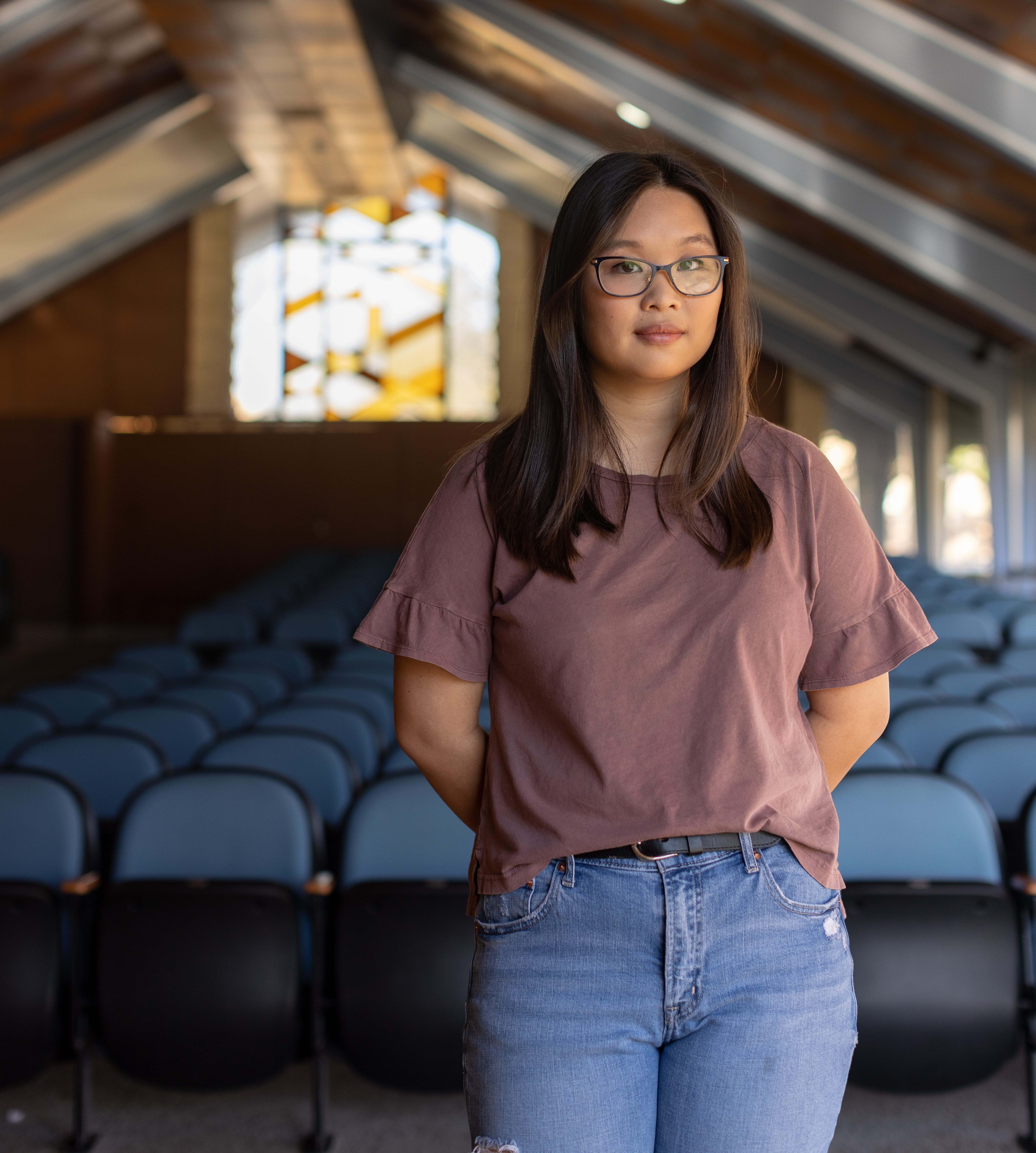 a photo of a woman leaning against a bunch of seats inside a chapel