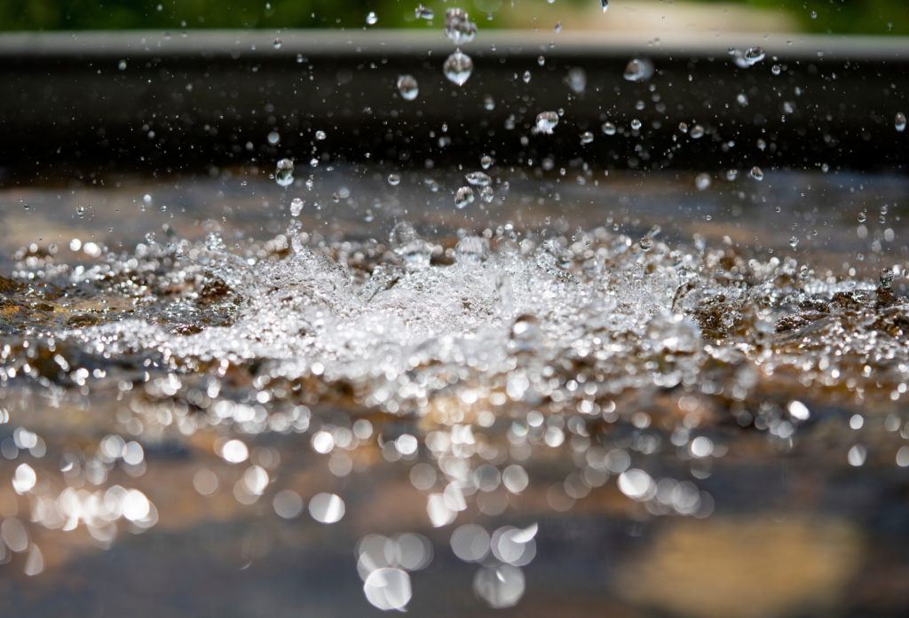 a photo of water drops falling into a larger pool of water below