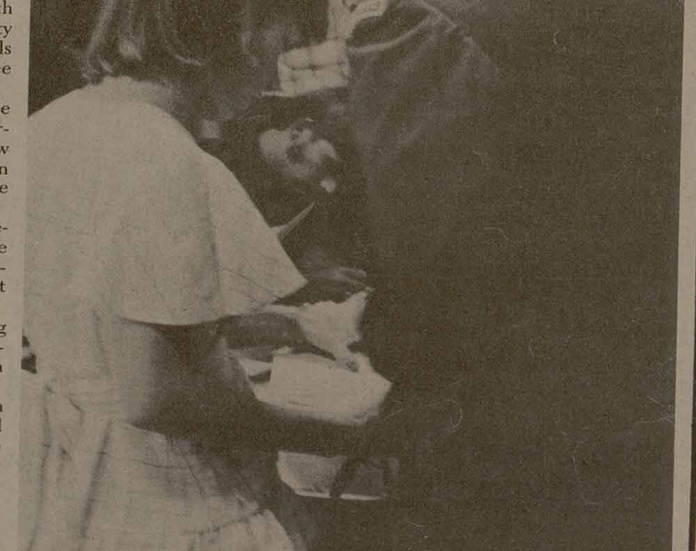 a newspaper clip with a photo showing the backs of a young woman and man in a military uniform