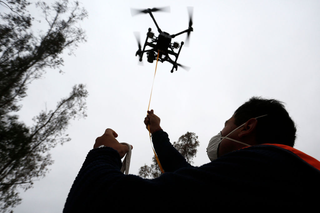 a drone flies in the air over a pilot on the ground