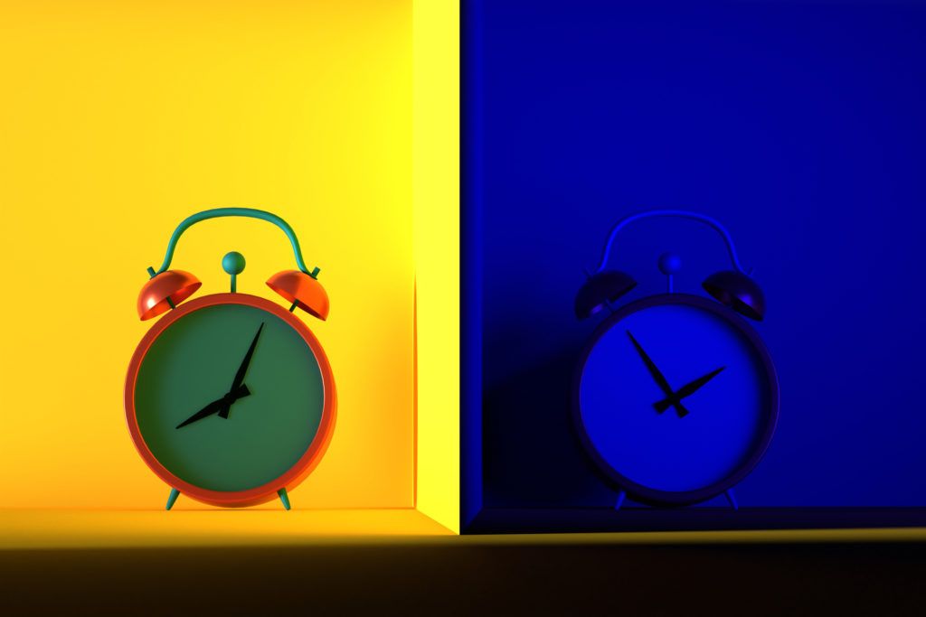 Two alarm clocks side-by-side against yellow and blue backgrounds representing day and night.