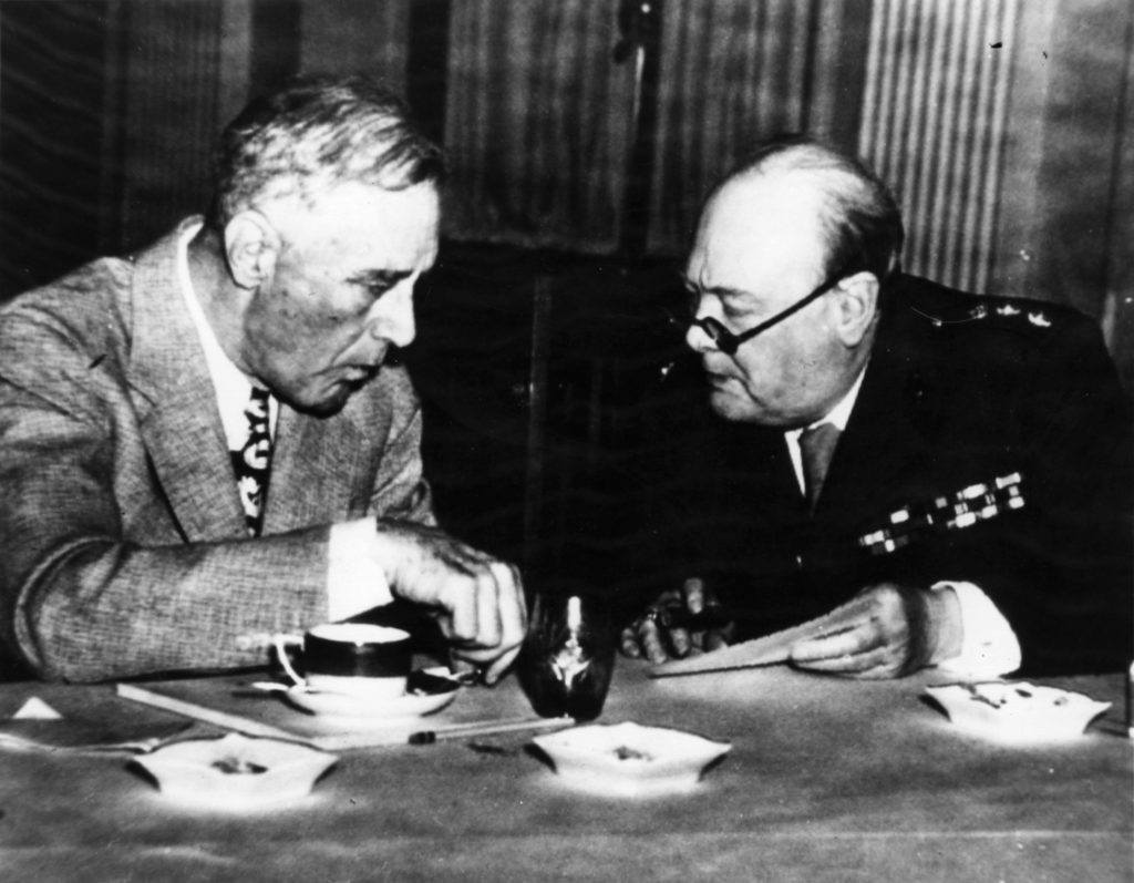 an old black and white photo showing winston churchill and franklin d Roosevelt sitting at a table having a conversation