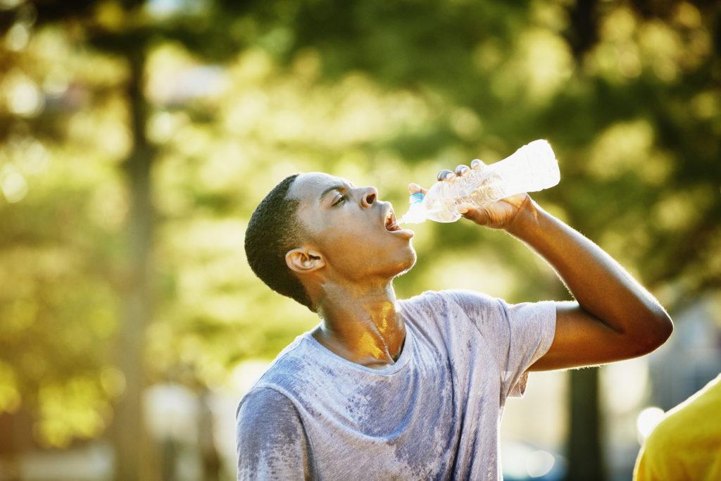 Young man drinking out of a water bottle on a sunny day