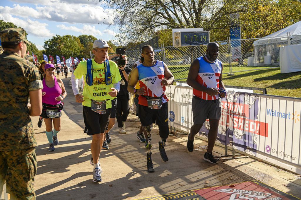 Cordani running in a marathon alongside an athlete with disabilities