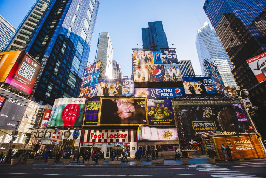 a photo of New York City's Times Square during the day, with a huge cluster of signs and billboards featuring brands such as Pepsi, LG, and Nickelodeon