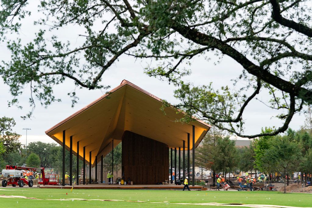 A large amphitheater and stage at the center of the park overlooking a grassy lawn
