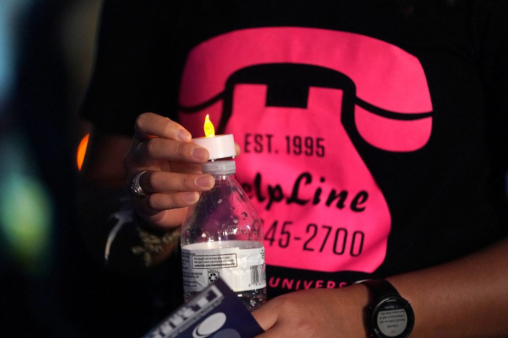 Close-up photo of someone wearing a T-shirt with a graphic of a pink telephone and the HelpLine phone number